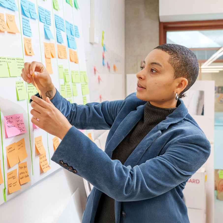 Ellis Aguilar working at a whiteboard covered in sticky notes
